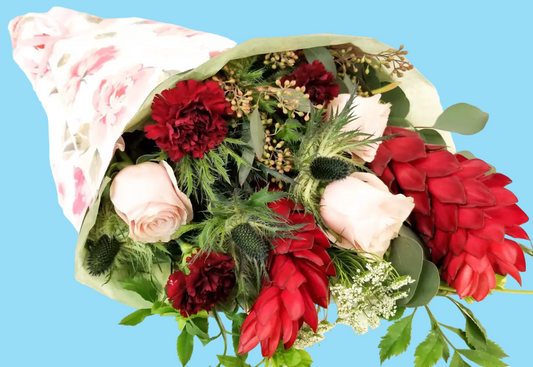 Bouquet of red and pink flowers with greenery on a white background